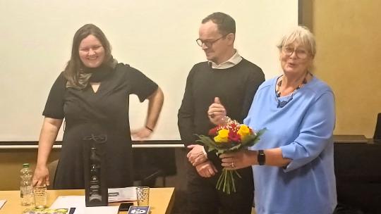 Dr. Heide-Rose Brückner übergibt einen Blumenstrauß an Claudia Schmidt und Martin Gibson-Kunze
